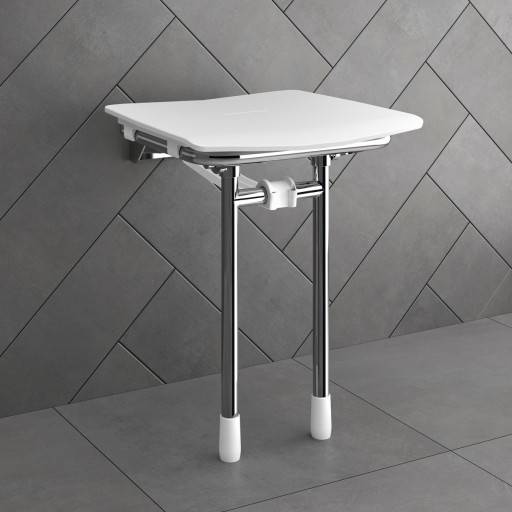 Si�ge de douche RUGAO blanc d�pli� contre un mur carrel� gris.