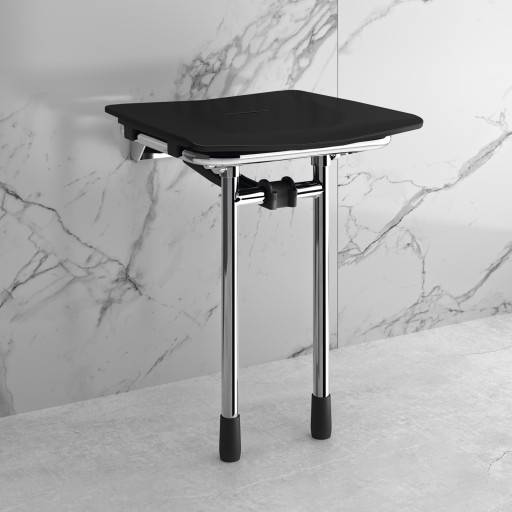 Si�ge de douche RUGAO noir d�pli� contre un mur clair effet marbre.